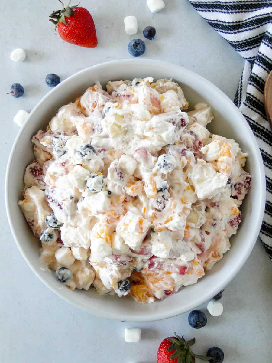 Top view of creamy fruit salad in round white serving bowl.