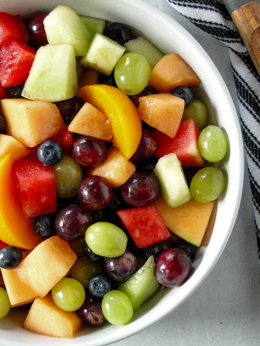 Close up top view of summer fruit salad in white serving bowl.