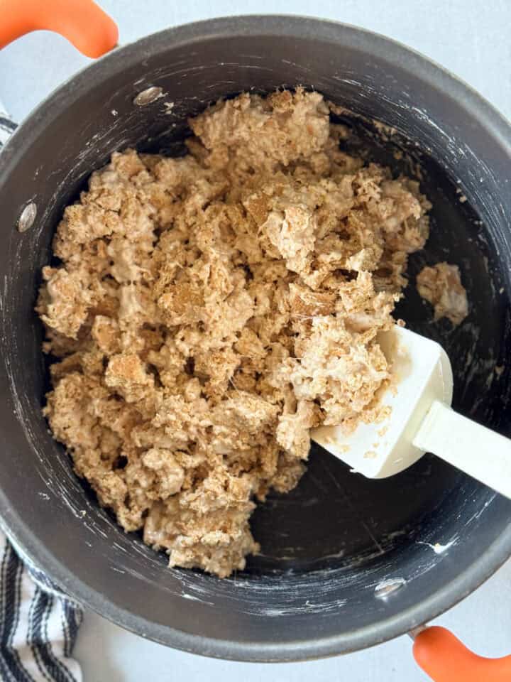 Marshmallows and graham crackers combined in large pot with spatula.