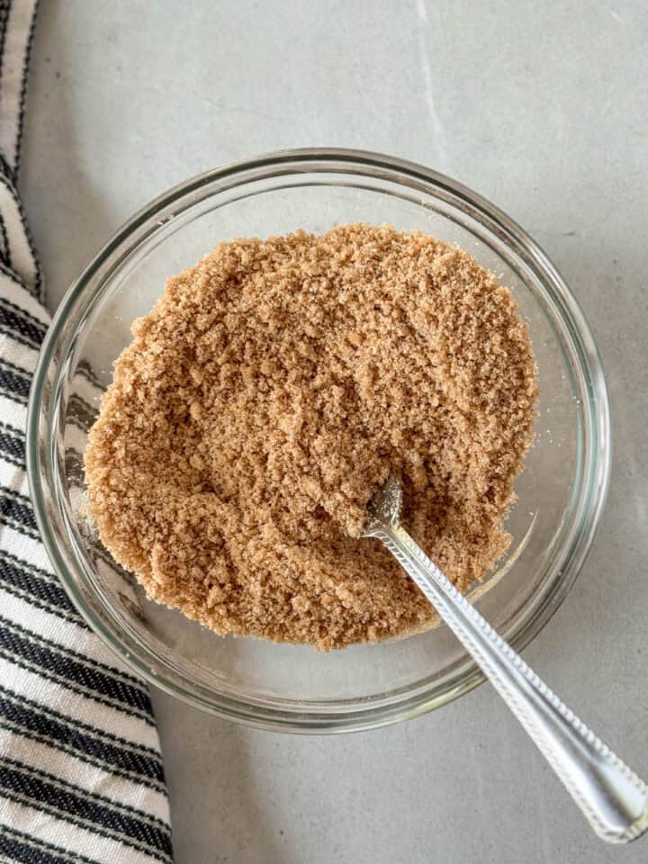Crumble topping mixed together in glass mixing bowl with fork.