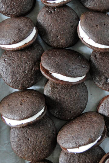 Close up top view of whoopie pies scattered and staggered on parchment paper.