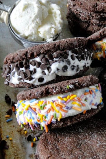 Top view of ice cream cookie sandwiches with mini chocolate chips and sprinkles with extra ice cream and cookies on the side.