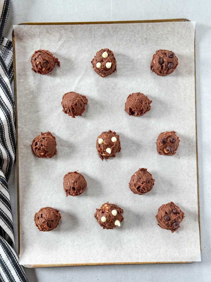 Cookie dough scoops on parchment lined cookie sheet.