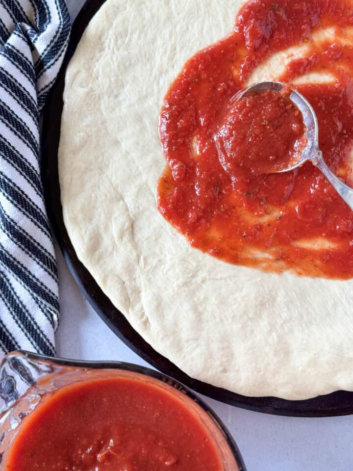 Pizza sauce being slathered on pizza dough.
