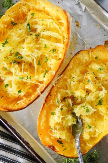 Oven roasted spaghetti squash on sheet pan with strands pulled and fork in one half.
