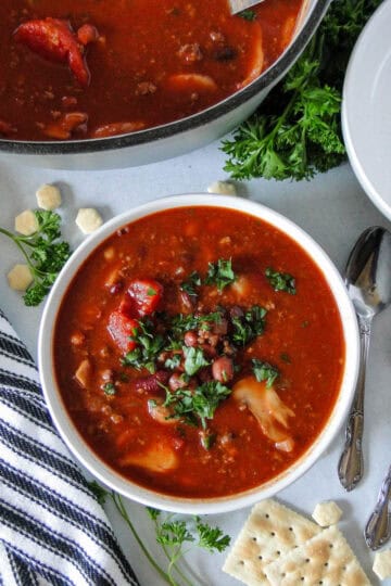 Top view of three bean chili in white round bowl next to dutch oven of chili.