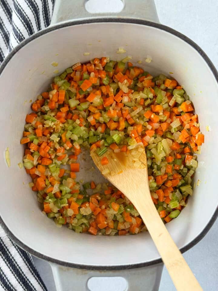 Veggies cooked in dutch oven with wooden spoon.
