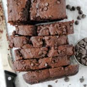Top view of double chocolate banana bread, half of it cut into slices with knife on the side.