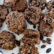No bake chocolate cookies in a pile on parchment paper with one cookie cut in half.