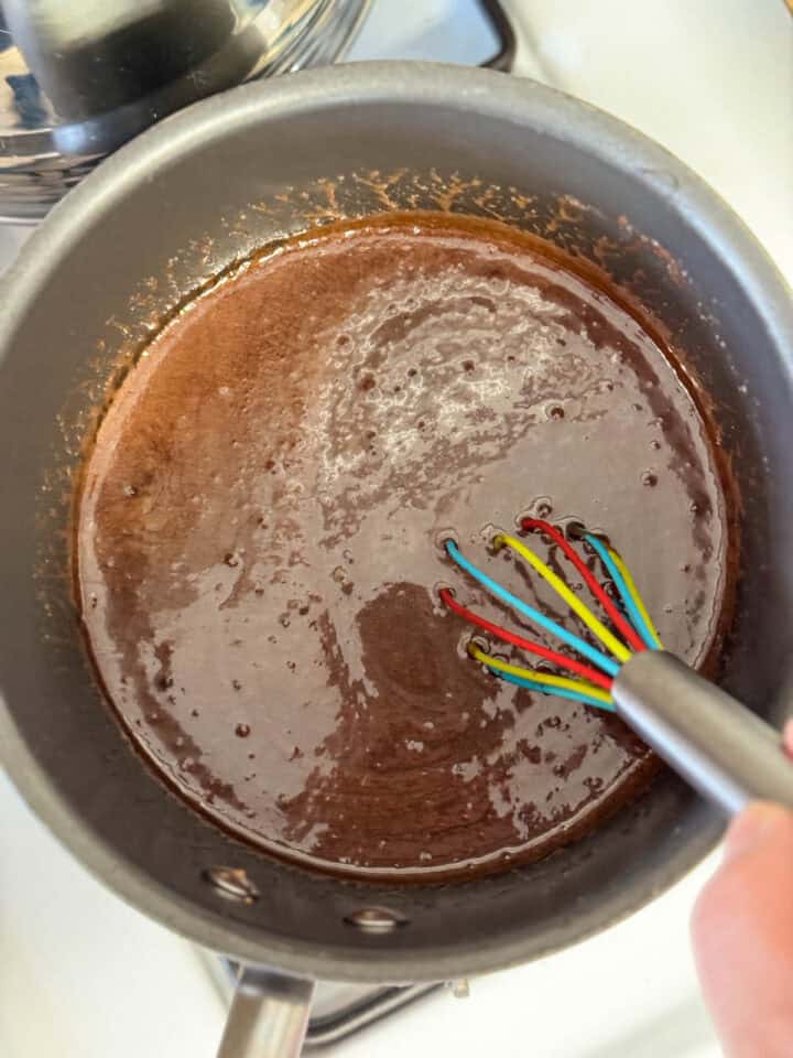 Chocolate mixture ingredients melted together in pot with whisk.
