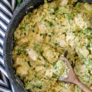 Top view of broccoli cheddar chicken orzo in skillet with wooden serving spoon in skillet.