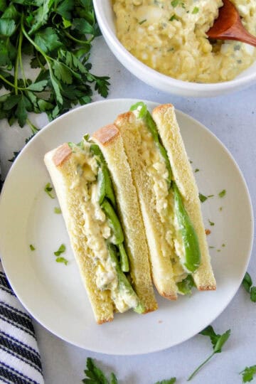Classic egg salad made into an old fashioned egg salad sandwich on white bread cut diagonal and set up to see center of sandwich.