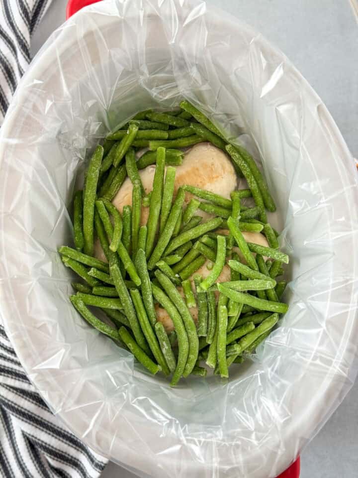 Frozen green beans added on top of seared chicken breasts in crock pot.