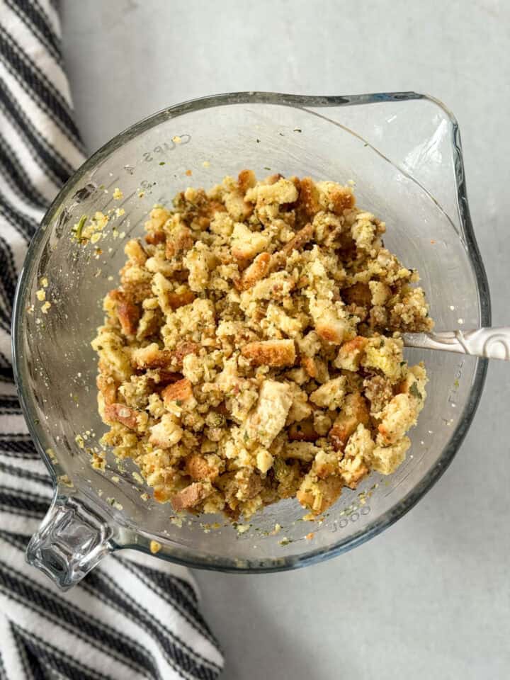 Stuffing mix ingredients combined in glass mixing bowl.