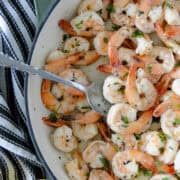 Garlic butter shrimp in skillet with serving spoon.