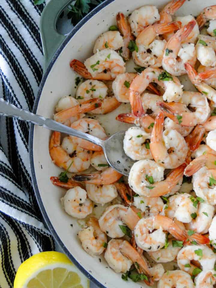 Garlic butter shrimp in skillet with serving spoon.