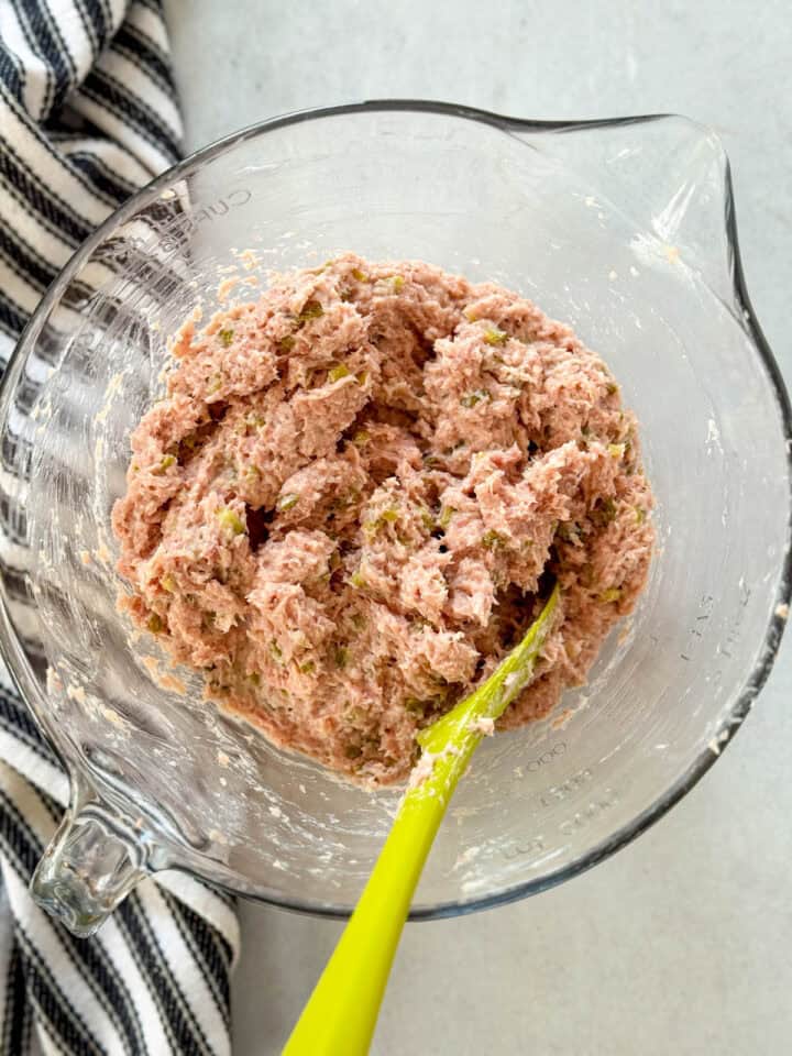 All ingredients mixed together in glass mixing bowl with green spatula.