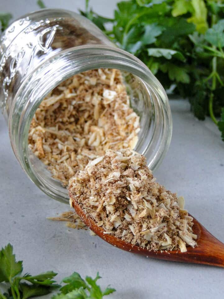 Close up side view of homemade onion soup mix spilling out of mason jar and some on spoon.