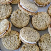 Homemade oatmeal crem pies scattered and layered on parchment paper.