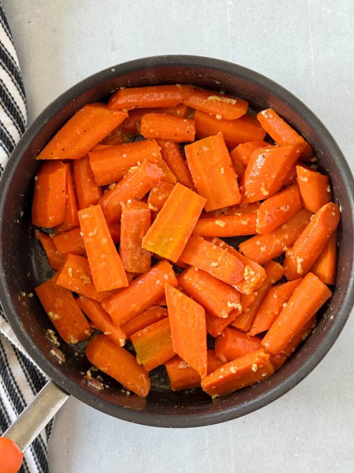 Cooked carrots in skillet sauteed with butter and garlic.