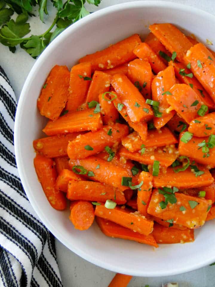 Close up top view of honey glazed carrots in white serving bowl.
