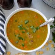 Top view of instant pot split pea soup in white bowl with spoon next to instant pot.