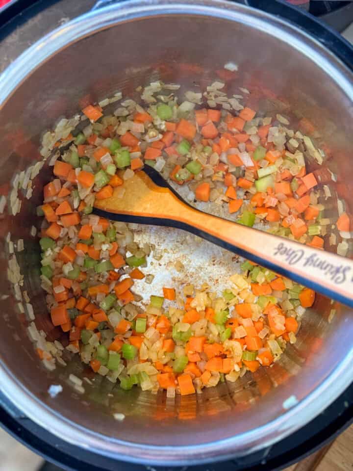 Cooked veggies in instant pot with wooden spoon.