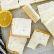 Top view of lemon sugar cookie bars sliced with some bars layered, one bar on its side and a bite taken out of one bar all sitting next to more sliced bars.