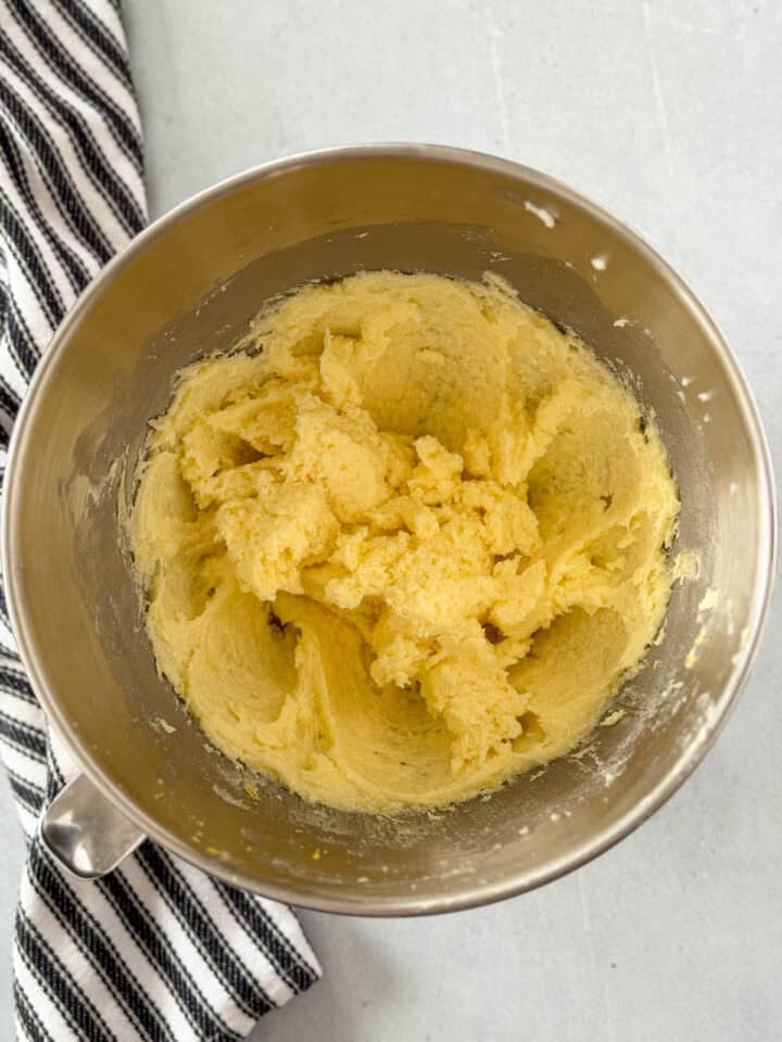Eggs and lemon added to creamed butter and sugar in large metal mixing bowl.