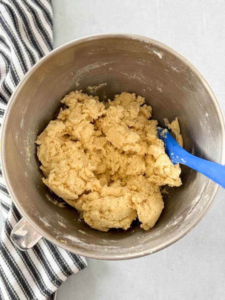 All dry ingredients combined to wet in metal mixing bowl with blue spatula.