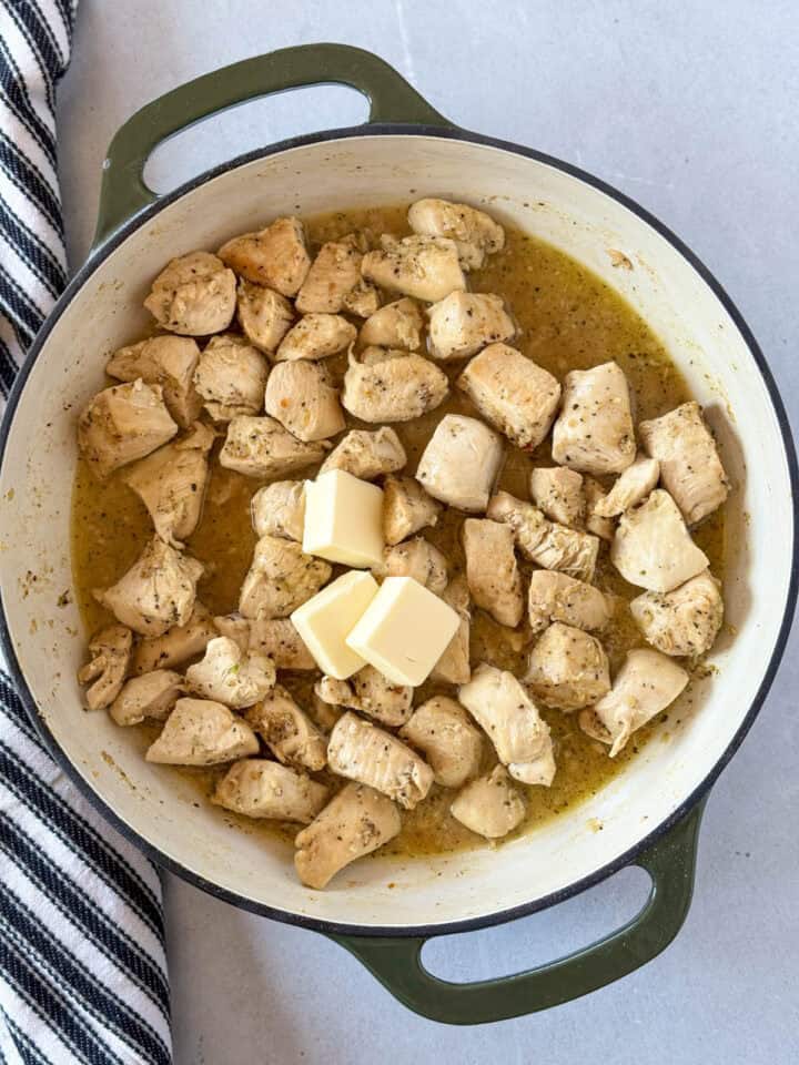 Butter added to cooked chicken in skillet.
