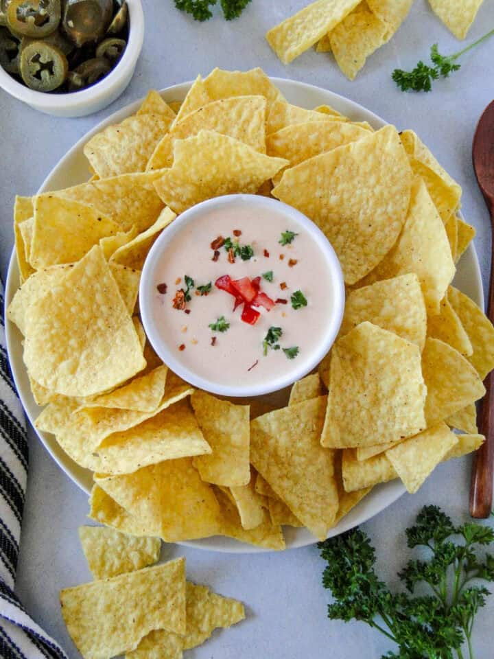 Top view of homemade queso dip in serving bowl surrounded by tortilla chips.