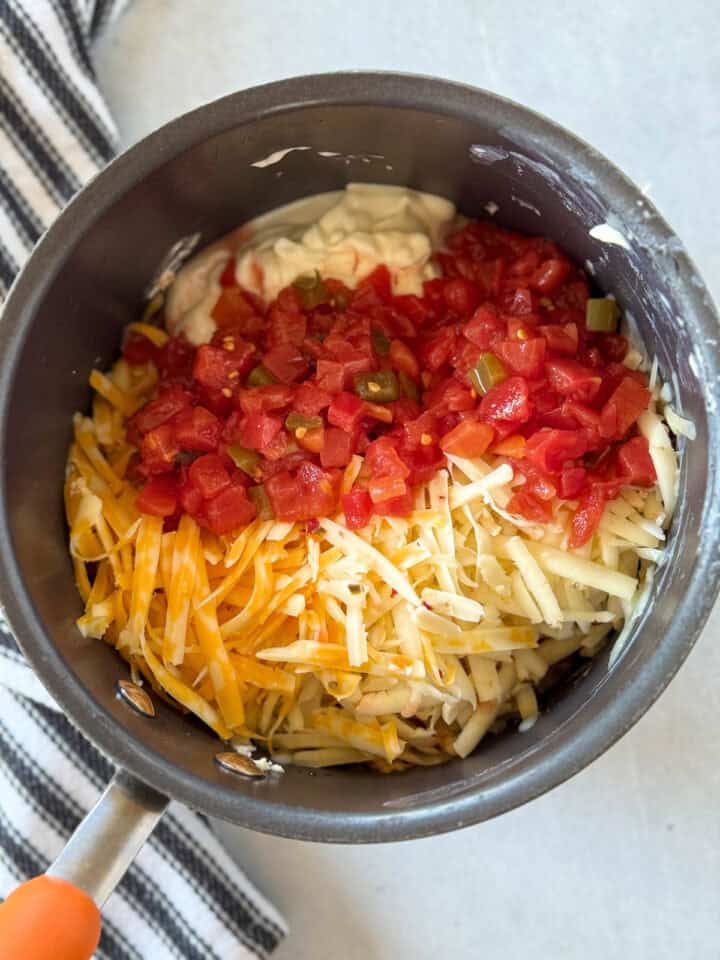 Shredded cheese and tomatoes added to pot.
