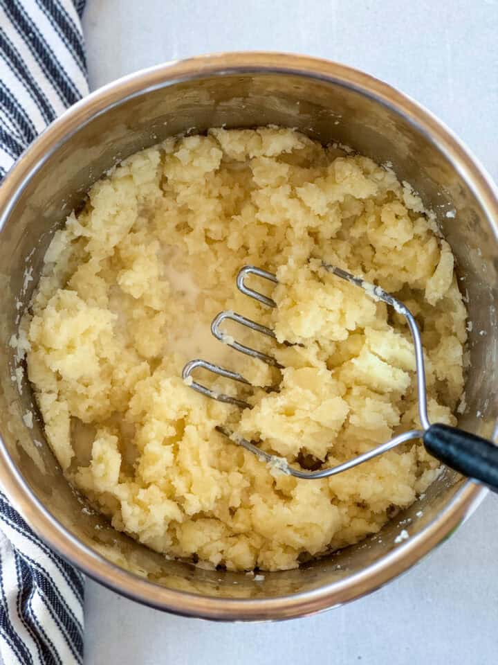 Milk and seasonings added to mashed potatoes and butter.