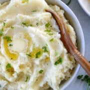 Top view of instant pot mashed potatoes in white serving bowl with wooden serving spoon in bowl.