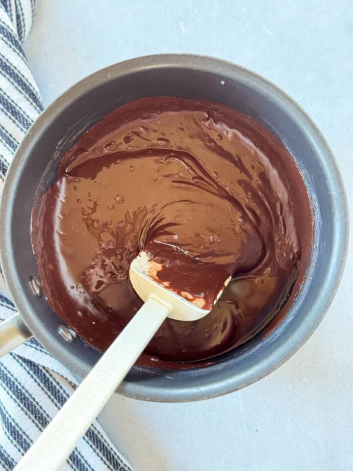 Melted chocolate mixture in pot with white spatula.