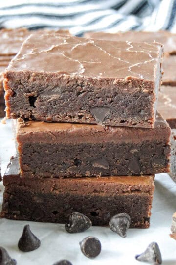 Close up side view of three frosted brownies stacked.