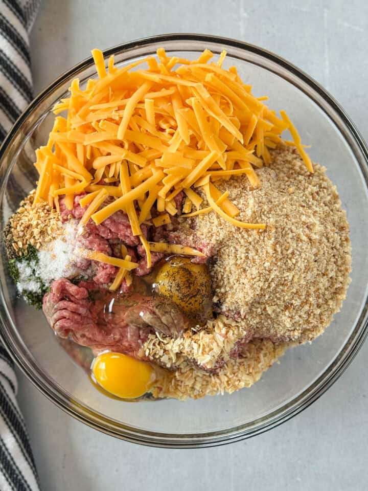 Meatloaf mixture ingredients in large glass mixing bowl.