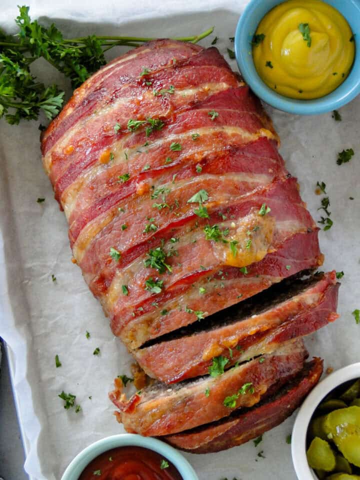 Close up top view of bacon wrapped meatloaf with a few slices off one end.