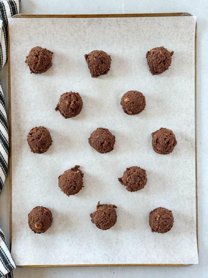 Cookie dough scoops on parchment lined cookie sheet.