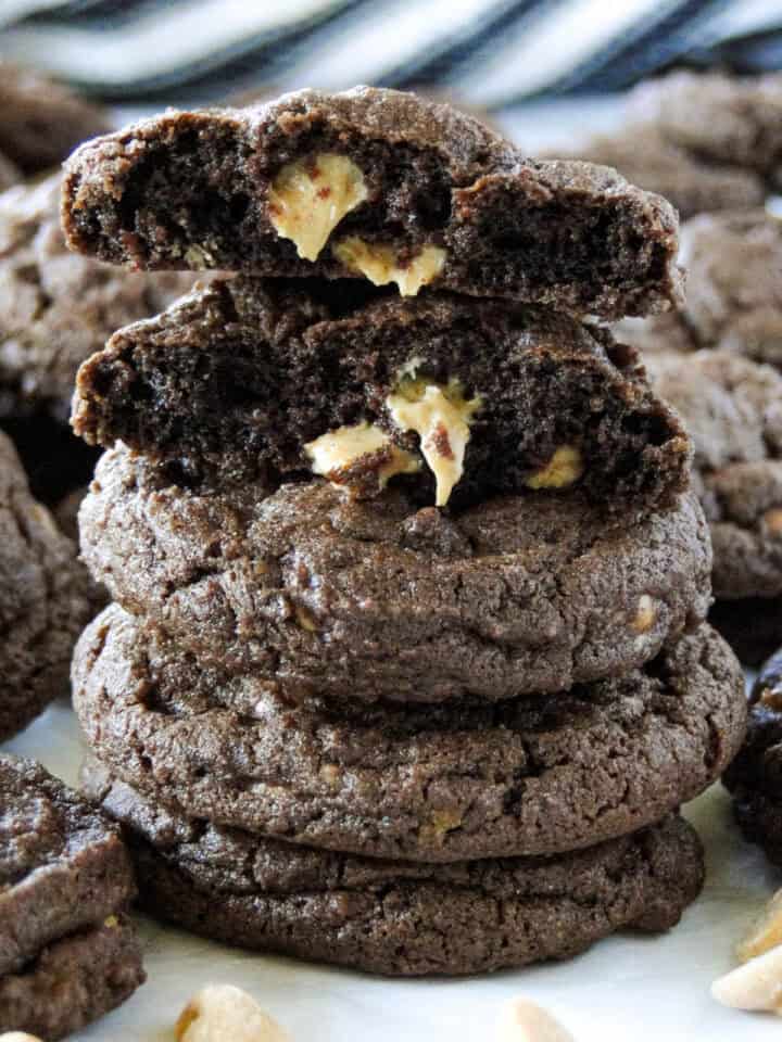 Four peanut butter chip chocolate cookies stacked with top cookie broken in half showing center of cookie.