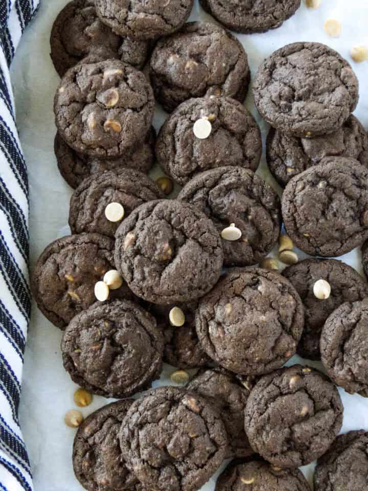 Peanut butter chip chocolate cookies scattered and layered on parchment paper.