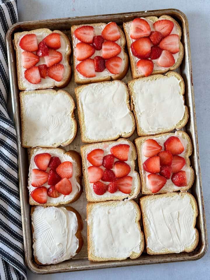 Macerated sliced strawberries placed on half of the cream cheese covered bread slices.