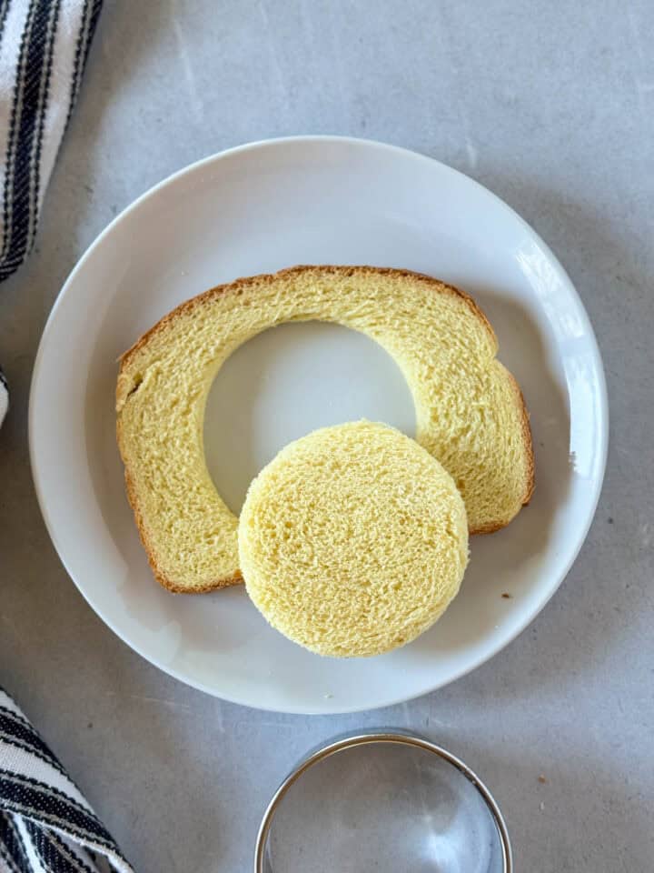 Center of bread cut out with biscuit cutter on white round plate.