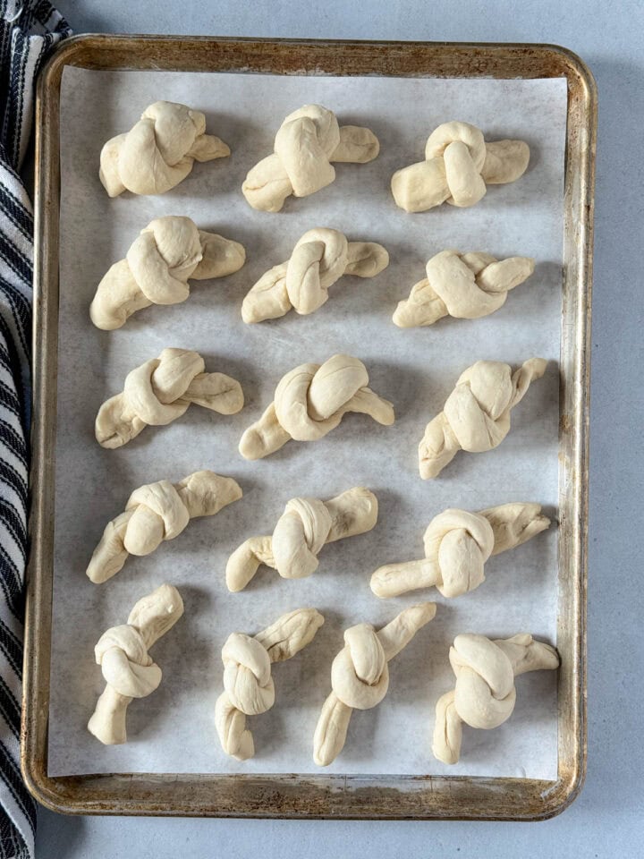 All bread ropes tied into knots placed in rows on sheet pan.